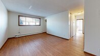 Located at 219 3rd Ave SW in Forest Lake, Minnesota, this two-bedroom, one-bathroom unit offers a practical and well-organized single-floor layout. The living room features warm hardwood-style flooring, a textured ceiling, and a window with wood-trimmed blinds that brings in natural light, along with baseboard heating for year-round comfort. Adjacent to the living area, the kitchen is equipped with rich dark wood cabinetry, granite-look countertops, a stainless steel refrigerator, and an electric range, all complemented by a ceiling fan overhead. A hallway connects the main living spaces to the private quarters and six closets, providing generous storage throughout. The primary bedroom offers carpeted flooring, a ceiling fan, and dual windows with wood-trimmed blinds, filling the room with natural light. The second bedroom also features carpet, a ceiling fan, and a large sliding-door closet. The bathroom is finished with classic white tile surrounding a full tub-shower combination and mosaic tile flooring. The unit's consistent use of warm wood tones, practical finishes, and well-distributed storage makes it a functional and comfortable living space.