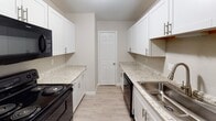 Located at 3110 Utah Pl in Greensboro, North Carolina, this single-floor residence offers a well-organized layout with a neutral, move-in-ready aesthetic throughout. The entry hallway sets a clean tone with light luxury vinyl plank flooring, white panel doors, and flush ceiling lighting that guides you into the main living areas.

The living room is generously proportioned, featuring wall-to-wall carpet and a large sliding glass door dressed with vertical blinds that allows natural light to fill the space. It connects openly to the kitchen, creating a practical flow between living and cooking areas. The galley-style kitchen is well-appointed with white shaker cabinetry, granite-look countertops, a stainless steel sink, and black appliances including a range and dishwasher. Light vinyl plank flooring and a textured ceiling complete the functional space.

The bedrooms are carpeted and finished with the same warm neutral tones found throughout the home. Each room benefits from windows fitted with horizontal blinds, providing natural light and privacy. The bathroom features a full tub and shower combination with a curved curtain rod, a white vanity, and light wood-style flooring, offering a clean and practical design. Throughout the space, consistent use of white trim, textured ceilings, and a cohesive color palette creates a comfortable and welcoming environment.