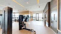 Located at 101 Chamomile Glen in Escondido, CA, this single-floor fitness center offers a generously sized, thoughtfully designed workout facility that caters to a full range of exercise disciplines. The space features a sleek, contemporary aesthetic with light hardwood-style flooring, crisp white walls, and a coffered ceiling accented by warm recessed lighting that creates an inviting yet energizing ambiance throughout.

The main workout area is expansive and open, housing a comprehensive selection of professional-grade strength machines, cable systems, free weights, dumbbells, a power rack, and adjustable benches. A dedicated cardio zone accommodates treadmills, stair climbers, and stationary bikes, while a functional training area provides space for dynamic exercises with access to medicine balls, kettle bells, and resistance equipment neatly organized on display racks.

Large floor-to-ceiling windows and glass sliding doors flood the interior with natural light and frame outdoor views of the surrounding landscape. Multiple exterior access points open to an outdoor terrace, further extending the workout experience. Ceiling fans provide additional air circulation throughout the space. Full-length mirrors along the walls visually expand the room and support proper form during training. The overall design balances functionality with a polished, modern finish, making this fitness center an exceptional facility for health and wellness.