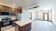 This well-appointed one-bedroom, one-bathroom unit in Waukee, Iowa offers a thoughtfully designed single-floor layout that maximizes both functionality and comfort. Light hardwood-style flooring flows consistently throughout the entire space, complemented by neutral-toned walls and dark-framed accents that lend a clean, contemporary aesthetic.

The open-concept kitchen and living area serves as the heart of the unit. The kitchen is equipped with stainless steel appliances, including a refrigerator, range, microwave, and dishwasher. Rich dark cabinetry is paired with crisp white countertops, open floating shelves, and a central island that provides additional prep and storage space. Recessed lighting keeps the kitchen bright and functional.

The living area features a ceiling fan and multiple windows that invite generous natural light, creating a welcoming and airy atmosphere. A glass-panel entry door further enhances the sense of openness.

The bedroom is a comfortable, well-sized retreat with dual windows that frame neighborhood views and a ceiling fan for year-round comfort. Dark-paneled doors lead to a dedicated closet with built-in shelving, offering practical organization. The bathroom is clean and efficiently laid out. Together, these spaces form a cohesive, modern unit ideal for those seeking a streamlined lifestyle in a contemporary residential community.