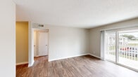 This single-floor residence in Decatur, Alabama offers a clean, functional layout with a consistent design language throughout. Wood-look plank flooring runs through the entire space, providing a warm, cohesive aesthetic complemented by neutral beige walls and crisp white trim and baseboards.

The open living area is generously proportioned, featuring a textured ceiling and a sliding glass door that opens to a private patio, allowing natural light to fill the room and providing outdoor views. A separate entrance door is also accessible from this area.

The kitchen is efficiently designed in a galley configuration, featuring white shaker-style cabinetry with brushed nickel hardware, light stone-pattern countertops, a stainless steel double sink with a gold-tone faucet, and stainless steel appliances including a refrigerator, range, and dishwasher.

The bedroom offers a comfortable, well-sized layout with a window that brings in natural light, a textured ceiling, and ample wall space. A second bedroom or additional room with its own entry door and wood-look flooring provides flexibility for various uses.

The bathroom is outfitted with a white vanity, a framed mirror with vanity lighting, a tub-shower combination, and matching wood-look flooring, maintaining the cohesive style found throughout the rest of the space.