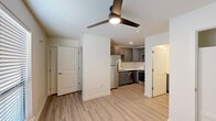 Located in Baton Rouge, Louisiana, this efficiently designed single-floor unit offers a thoughtfully utilized layout that includes a kitchen and a full bathroom. Light wood-look flooring runs throughout the space, creating a warm, cohesive aesthetic that complements the clean white walls and crisp trim.

The kitchen is a standout feature, outfitted with gray shaker-style cabinetry, white quartz countertops, a stainless steel undermount sink with a pull-down faucet, and a full suite of stainless steel appliances — including a refrigerator, range, microwave, and dishwasher. Recessed lighting enhances the kitchen's functionality and modern appeal.

The living area is bright and airy, benefiting from large windows dressed with horizontal blinds that allow for natural light control. A sleek, matte black ceiling fan with an integrated light fixture provides both air circulation and ambient lighting. A wall-mounted mini-split unit ensures efficient climate control.

The bathroom is clean and contemporary, featuring a white tub/shower combo with brushed nickel fixtures, a white quartz vanity countertop, gray cabinetry, and wood-look flooring that ties the space together. Overall, the unit presents a fresh, modern interior well-suited for comfortable everyday living.