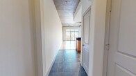 Located in Baltimore's vibrant Fell's Point area, this one-bedroom, one-bathroom residence blends industrial character with modern finishes across a well-appointed single floor. The open-concept living and dining area is anchored by striking exposed concrete ceilings with visible ductwork and track lighting, polished hardwood floors, and expansive floor-to-ceiling windows with sliding glass door access that flood the space with natural light and frame impressive panoramic city skyline views. The kitchen is thoughtfully designed with warm wood cabinetry, dark granite countertops, a large peninsula with bar seating, and a full suite of stainless steel appliances including a refrigerator, range, microwave, and dishwasher. Slate tile flooring connects the kitchen and entry hallway, complementing the industrial aesthetic. The generously sized bedroom features the same exposed concrete ceiling and hardwood floors, with a sliding glass door providing additional outdoor access. The full bathroom offers a soaking tub with tile surround, a wood vanity with dark granite countertop, a framed mirror, and matching slate tile floors. Two closets and an in-unit laundry area add practical convenience to this architecturally distinctive urban residence.