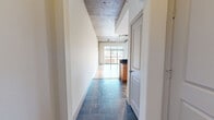 Located in Baltimore's vibrant Fell's Point area, this one-bedroom, one-bathroom residence blends industrial character with modern finishes across a well-appointed single floor. The open-concept living and dining area is anchored by striking exposed concrete ceilings with visible ductwork and track lighting, polished hardwood floors, and expansive floor-to-ceiling windows with sliding glass door access that flood the space with natural light and frame impressive panoramic city skyline views. The kitchen is thoughtfully designed with warm wood cabinetry, dark granite countertops, a large peninsula with bar seating, and a full suite of stainless steel appliances including a refrigerator, range, microwave, and dishwasher. Slate tile flooring connects the kitchen and entry hallway, complementing the industrial aesthetic. The generously sized bedroom features the same exposed concrete ceiling and hardwood floors, with a sliding glass door providing additional outdoor access. The full bathroom offers a soaking tub with tile surround, a wood vanity with dark granite countertop, a framed mirror, and matching slate tile floors. Two closets and an in-unit laundry area add practical convenience to this architecturally distinctive urban residence.