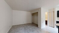 This single-floor unit at 3802 N Flowing Wells Rd in Tucson, Arizona offers a clean and functional layout designed for comfortable everyday living. Throughout the space, light-toned marble-style tile flooring provides a cohesive and easy-to-maintain surface.

The living area is open and simply designed, featuring neutral white walls that create a bright atmosphere. A wall-mounted air conditioning unit provides climate control, and a large window with vertical blinds allows natural light to fill the room. A pendant light fixture and a pass-through breakfast bar connect the living area to the kitchen, adding a social and practical element to the layout.

The kitchen is well-appointed with dark cabinetry contrasting against white countertops, a stainless steel sink, a white electric range with overhead ventilation, and a dishwasher. A window above the counter brings in additional natural light, making the kitchen feel airy and functional.

The bedroom offers a comfortable, open space with a built-in closet featuring a hanging rod for convenient storage. The room connects directly to the bathroom, which is outfitted with a tiled shower-tub combination equipped with safety grab bars, a toilet, and a vanity with a granite-style countertop and a mirrored medicine cabinet above. The consistent tile flooring carries throughout, tying the space together with a unified aesthetic.