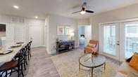 This single-story residence showcases a cohesive contemporary design throughout, unified by wood-look plank flooring, neutral gray walls, and white trim. The open-concept kitchen serves as a functional centerpiece, featuring dark espresso cabinetry, granite countertops, a tile backsplash, and stainless steel appliances including a refrigerator, range, and microwave. A granite-topped island with seating provides additional workspace and casual dining space, while a dedicated pantry offers ample storage. The adjoining living area is bright and welcoming, benefiting from a ceiling fan, large windows, and a glass-paned door that invites natural light and outdoor access. The bedrooms are comfortably proportioned, each featuring wood-look flooring, windows with natural light, and ceiling fans for added comfort. Two full bathrooms mirror each other in design, both outfitted with dark cabinetry, granite-topped vanities, and tub-shower combinations. A dedicated laundry area houses a full-sized washer and dryer beneath dark overhead cabinetry, providing convenient in-unit functionality. The overall layout flows efficiently, offering a practical and attractively finished living environment.