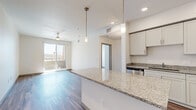 This well-appointed 1-bedroom, 1-bathroom unit offers a thoughtfully designed layout spread across a single floor. The open-concept kitchen and living area serves as the heart of the space, featuring warm wood-look flooring, white shaker cabinetry, granite countertops, a large kitchen island, and a full suite of stainless steel appliances including a range, microwave, dishwasher, and refrigerator. Pendant lighting over the island adds a modern touch, while recessed ceiling lights provide ample illumination. The living area benefits from natural light and direct access to a private balcony through sliding glass doors, offering outdoor views of the surrounding area. A ceiling fan overhead enhances comfort throughout. The bedroom is a comfortable, well-lit retreat with two windows, a ceiling fan, and a spacious walk-in closet with built-in shelving. The full bathroom is clean and functional, featuring a granite-topped vanity with white cabinetry, a tub-shower combination, and wood-look flooring that ties in with the rest of the unit. A hallway connects the main living spaces, completing this efficient and modern single-level layout.