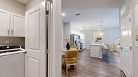 This well-appointed 2-bedroom, 2-bathroom residence in White House, Tennessee offers a thoughtfully designed single-floor layout that maximizes comfort and functionality. Rich hardwood-style flooring flows throughout, anchoring the home's clean, contemporary aesthetic with neutral tones and crisp white trim.

The open-concept kitchen is a standout feature, showcasing white shaker cabinetry, light quartz countertops, a large breakfast bar with seating, stainless steel appliances — including a French door refrigerator, electric range, and built-in microwave — and elegant pendant lighting. The adjacent dining area transitions seamlessly into the living room, which is bright and welcoming with a door providing direct access to a private outdoor space.

Both bedrooms are comfortably sized, with the primary bedroom offering generous proportions, natural light from a large window with neighborhood views, and plush carpeting. Each bathroom features white vanity cabinetry with quartz countertops and a tub/shower combination. A dedicated laundry room provides in-unit washer and dryer hookups with overhead cabinetry for added storage. The home's cohesive design and practical layout make it an ideal residence in White House, TN.