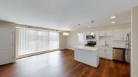 Located at 6230 Stumph Rd in Parma Heights, Ohio, this thoughtfully updated single-floor residence offers a clean, modern aesthetic with functional design throughout. The open-concept living and kitchen area serves as the heart of the space, anchored by rich hardwood flooring that extends across the main living zone. A floor-to-ceiling vertical blind window wall floods the living area with natural light and provides views of the surrounding neighborhood. The kitchen is well-appointed with crisp white shaker cabinetry, a white subway tile backsplash, light quartz countertops, and a central island with a marble-veined quartz surface. Stainless steel appliances — including a range, microwave, dishwasher, and refrigerator — complete the modern kitchen package. Pendant and recessed lighting add warmth and functionality to the space. The bedroom features hardwood flooring, double closets, and direct hall access, while a secondary carpeted room with a window offers versatility as a bedroom or office. Two bathrooms serve the unit: one with a glass-enclosed walk-in shower and lighted vanity mirror, and another with a full soaking tub, tiled surround, and coordinating finishes. Neutral tones and consistent materials create a cohesive, move-in-ready environment throughout.