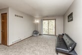 This single-floor unit offers a well-organized layout that balances open living space with functional room design. The living area is generously sized, featuring neutral-toned carpet, a textured ceiling, and a ceiling fan that enhances air circulation. A large sliding glass door fills the room with natural light and provides direct access to a private balcony overlooking a lush, tree-lined outdoor setting. A hallway connects the living space to the remaining rooms, with warm-toned wooden doors adding a consistent design element throughout.

The galley-style kitchen is efficiently arranged, featuring dark wood cabinetry, white laminate countertops, tile backsplash, and light vinyl flooring. It is equipped with a full suite of appliances, including a refrigerator, stove, and dishwasher, along with ample cabinet and counter space. A pass-through counter opens toward the living and dining area.

The bedroom offers a comfortable, carpeted space with a large window framing views of surrounding greenery. Built-in shelving and a sliding-door closet with a full rod provide practical storage. The bathroom includes a tub-shower combination, a single vanity with under-cabinet storage, and a mirrored medicine cabinet.