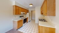 Located at 1443 Stowell Dr in Rochester, NY, this single-floor residence offers a well-organized layout with a practical and comfortable design throughout. The living area is generously sized, finished with neutral-toned carpet and featuring a textured ceiling. Large sliding glass doors open to a private balcony, filling the space with natural light and providing pleasant views of the surrounding trees and outdoor scenery. A secondary window in the adjoining area further enhances the brightness of the living space.

The kitchen is thoughtfully equipped with warm oak cabinetry offering ample storage, light countertops, a stainless steel sink, and white appliances including a range and refrigerator. The floor is finished with classic white ceramic tile, adding a clean, functional quality to the space.

The bedrooms are carpeted and well-proportioned, each with windows that invite natural light and views of the lush outdoor greenery. The rooms are served by a bathroom featuring a wood-toned vanity with under-sink storage, a wall mirror with overhead lighting, and tile flooring that coordinates with the kitchen.

Throughout the space, a consistent neutral color palette of warm beige and white tones creates a cohesive and inviting atmosphere. The layout, as seen in the floor plan, flows efficiently between living, dining, kitchen, and private bedroom areas.