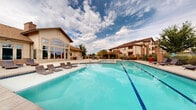 Located at 1600 S Taft Ave in Loveland, Colorado, this resort-style pool area is a thoughtfully designed outdoor amenity space that offers a full suite of leisure features under the open Colorado sky. At the heart of the space is a generously sized swimming pool with striking blue tile accents, complemented by a separate circular hot tub for relaxation. Surrounding the pool, a broad concrete deck provides ample room for sunbathing, furnished with multiple wicker and padded lounge chairs positioned to take in the open views and lush greenery.

A handsome wooden pergola anchors one end of the patio, providing shaded seating beneath its open-beam canopy, with metal bistro tables and chairs arranged for casual outdoor dining or socializing. Decorative brick columns topped with lanterns and large ornamental planters filled with vibrant foliage add color and character throughout the space.

Adjacent to the main clubhouse building — clad in natural stacked stone and siding with expansive floor-to-ceiling windows — a built-in outdoor grill station with granite countertops offers a convenient space for outdoor cooking and entertaining. The entire area is enclosed by a wrought-iron fence with brick pillar accents, providing both security and a polished, cohesive aesthetic that elevates the overall ambiance of the outdoor space.