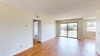 Located on Riverside Drive in the heart of Los Angeles, CA, this one-bedroom, one-bathroom unit offers a well-organized, single-floor layout with hardwood-style flooring that flows consistently throughout every room. The open living and dining area is bright and airy, drawing in generous natural light through large sliding glass doors that open onto a private balcony with outdoor views of the surrounding neighborhood. A secondary window further enhances ventilation and daylighting in the space. The galley-style kitchen is efficiently designed with warm wood cabinetry spanning floor to ceiling on both sides, white appliances including a gas range and dishwasher, tile backsplash, and a light-colored countertop — offering ample storage and workspace. A hallway connects the main living area to the private quarters, which include a well-sized bedroom featuring its own window with natural light and views, plus a dedicated closet for storage. The full bathroom is equipped with a tub-shower combo enclosed by sliding glass doors, a wide vanity with a large mirror, and matching hardwood-style flooring. Textured ceilings are present throughout, and the neutral warm-toned walls create a clean, welcoming ambiance throughout the entire unit.
