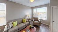 This single-floor residence offers a thoughtfully designed layout with a clean, modern aesthetic. The open-concept living and kitchen area serves as the heart of the unit, where warm hardwood-style flooring flows seamlessly throughout. The living room is bright and inviting, featuring large windows that allow abundant natural light and offer views of the surrounding neighborhood. A dedicated seating area provides a comfortable and functional space for relaxing or entertaining.

The kitchen is well-equipped and efficient, showcasing white shaker-style cabinetry, granite-look countertops, a classic subway tile backsplash, and a full suite of stainless steel appliances including a refrigerator, range, and built-in microwave. A breakfast bar with seating connects the kitchen to the living space, enhancing the open, social atmosphere.

The unit includes two bedrooms, each finished with plush carpeting and windows that bring in natural light. One bedroom features a walk-in closet accessible through sliding doors, offering generous storage. The full bathroom is clean and functional, featuring a white vanity, tile flooring, and a shower-tub combination with a marble-patterned curtain. Neutral tones and consistent finishes throughout the unit create a cohesive and welcoming ambiance.
