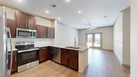 Located at 2151 Prairie Dr in Prosper, TX, this well-appointed 2-bedroom, 2-bathroom residence offers a thoughtfully designed single-level layout. The open-concept living area seamlessly connects the kitchen, dining, and living spaces, creating an inviting and functional environment. The kitchen is a standout feature, showcasing rich dark-wood cabinetry, granite countertops, a peninsula with a double sink, and a full suite of stainless steel appliances including a refrigerator with ice maker, electric range, built-in microwave, and dishwasher. Hardwood-style flooring flows throughout the main living areas, complemented by recessed lighting and a ceiling fan. French doors open from the living room to a private outdoor area, allowing natural light to pour in. Both bedrooms are carpeted for comfort, each featuring ceiling fans and windows that bring in additional natural light. The generously sized primary bedroom offers ample space for furnishings. The bathrooms feature granite-topped dark-wood vanities with hardwood-style flooring, and the secondary bath includes a tub/shower combination. Four closets, a dedicated laundry area, and a connecting hallway complete this efficiently designed residence.