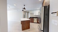Located at 2432 Albany Ave in West Hartford, CT, this well-appointed one-bedroom, one-bathroom residence offers a thoughtfully designed single-floor layout. Light-toned hardwood-style flooring runs throughout, creating a cohesive and airy feel across all rooms.

The kitchen is a standout feature, showcasing a contemporary two-tone design with rich wood-grain lower cabinetry and sleek white upper cabinets, all complemented by dark countertops and a subtle tile backsplash. A full suite of stainless steel appliances — including a refrigerator, range, microwave, and dishwasher — adds a polished, modern touch. A freestanding kitchen island with a white countertop and built-in wine rack serves as both a functional workspace and a visual centerpiece, accented by stylish pendant lighting overhead.

The living room is generously proportioned, bathed in natural light through large sliding glass doors that open to an outdoor view, with a tray ceiling detail adding architectural interest. The bedroom is spacious and bright, featuring windows that draw in natural light and neutral-toned walls that create a calm, restful atmosphere.

The bathroom features a full soaking tub with clean, floor-to-ceiling white rectangular tile surround and chrome fixtures, delivering a crisp, modern aesthetic. Overall, the space combines contemporary finishes with a warm, welcoming ambiance.