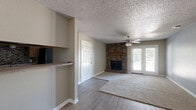This single-story, 2-bedroom, 1-bathroom home offers a functional and comfortable layout across a well-utilized floor plan. The living room serves as the heart of the home, highlighted by a striking floor-to-ceiling stacked stone fireplace with a wood mantle and hearth. French doors flood the space with natural light and provide outdoor access, while a ceiling fan and textured ceiling complete the room. Carpet flooring adds warmth underfoot throughout the living and bedroom areas, with hard surface flooring in the transitional spaces.

The kitchen is equipped with wood cabinetry, granite-style countertops, a tile mosaic backsplash, and black appliances including a full-size refrigerator. A window above the sink area brings in additional natural light. A pass-through or built-in shelf connects the kitchen to the adjacent living area, enhancing the open feel.

Both bedrooms are carpeted and include ceiling fans. The primary bedroom features a large window with outdoor views and a dedicated closet. A second closet provides additional storage elsewhere in the home. The bathroom includes a granite-topped vanity, a full tub-shower combination with large-format tile surround, and a built-in niche. Throughout the home, neutral tones and consistent finishes create a cohesive and move-in-ready atmosphere.