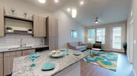 This thoughtfully designed single-floor residence offers a seamless blend of modern aesthetics and functional living. The open-concept layout connects the kitchen and living area, creating an inviting, airy atmosphere enhanced by vaulted ceilings and recessed lighting. The kitchen is a standout feature, showcasing light wood cabinetry, granite countertops, a classic subway tile backsplash, stainless steel appliances, and a central island with built-in shelving — ideal for both cooking and casual dining. Warm hardwood-style flooring flows throughout the main living areas, adding continuity and a contemporary feel. The living room is bright and welcoming, with large windows that allow generous natural light to fill the space, complemented by a ceiling fan and a glass door providing additional access to the exterior. The bedroom is carpeted for comfort, featuring multiple windows that frame outdoor views, a ceiling fan, and direct access to a spacious walk-in closet with built-in shelving. The bathroom is finished with dark wood cabinetry, granite countertops, and hardwood-style flooring, connecting conveniently to the bedroom. An in-unit laundry area completes this well-equipped residence, offering a practical and polished living experience.
