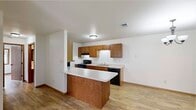This single-floor, 2-bedroom, 2-bathroom residence offers a practical and comfortable layout with consistent light hardwood flooring throughout. The combined kitchen and dining area serves as a functional hub, featuring warm-toned oak cabinetry, white laminate countertops, a peninsula with additional workspace, a double basin sink, and black appliances including a range, dishwasher, and refrigerator. The living area is bright and open, highlighted by a sliding glass patio door that invites natural light and outdoor access. Both bedrooms are well-sized, with the primary bedroom offering two windows that provide ample natural light and views of the surrounding area. Each bedroom is complemented by its own dedicated walk-in closet, outfitted with multi-level wire shelving systems that maximize storage capacity. The two bathrooms are clean and functional, each featuring a tub-shower combination, toilet, and a vanity with white countertop and wood cabinetry. Wood-framed door and window trim adds a cohesive warmth throughout the space. The overall design is straightforward and efficient, making effective use of every square foot while maintaining a neutral palette that suits a variety of furnishing styles.