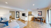 This 710 square foot apartment in Santa Monica offers a blend of comfort and style. The open-plan living area combines the living room, dining room, and kitchen, creating a spacious feel. The kitchen boasts light wood cabinetry, granite countertops, and stainless steel appliances, perfect for culinary enthusiasts.

The living room is adorned with a plush sectional sofa, modern coffee table, and vibrant artwork depicting local beach scenes, adding a touch of coastal charm. Large windows and recessed lighting ensure ample natural and artificial light throughout the space.

The bedroom, spanning 210 square feet, features a comfortable bed, ample storage, and a wall-mounted TV for entertainment. The bathroom showcases a combination of tile and wood elements, with a glass-enclosed shower and modern fixtures.

Hardwood floors run throughout the main living areas, while the bedroom is carpeted for added comfort. A sliding glass door in the dining area leads to a small balcony, offering views of palm trees and hinting at the nearby ocean atmosphere.

The apartment's location on Ocean Avenue puts residents within easy reach of Santa Monica's famous beach and pier, making it an ideal home for those seeking a blend of urban convenience and coastal living.