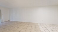Located in Miami, FL, this single-floor residence offers two bedrooms and two bathrooms within a well-organized layout. Light-toned ceramic tile flooring runs consistently throughout the home, contributing to a clean, cohesive aesthetic. The open living and dining area is generously proportioned, featuring crisp white walls and a sliding glass door that leads to a private balcony, allowing natural light to fill the space and providing a view of surrounding greenery. The kitchen is efficiently designed with white cabinetry, ample upper and lower storage, a range, and a sink—keeping the workspace functional and tidy. The primary bedroom is notably spacious and includes a walk-in closet fitted with built-in shelving and hanging rods, offering substantial storage capacity. A total of five closets are distributed throughout the home, ensuring plentiful storage options. The second bedroom is well-sized with a window that brings in natural light. Both bathrooms are cleanly finished, with one featuring a tiled walk-in shower with a marble-accented threshold. A hallway connects the private areas of the home, maintaining a clear and logical flow between spaces. The overall ambiance is bright, neutral, and move-in ready.