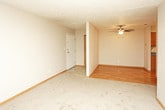 This single-floor unit offers a practical and well-organized layout designed for comfortable everyday living. The living area serves as the central hub of the space, featuring durable laminate wood flooring, a ceiling fan for year-round comfort, and seamless access to the kitchen and entry. Neutral-toned walls and textured ceilings are consistent throughout, lending a cohesive and understated aesthetic to every room.

The galley-style kitchen is efficiently arranged with oak cabinetry lining both walls, providing generous storage above and below. Bold blue laminate countertops add a distinctive touch, complemented by a double-basin sink, a white refrigerator, and a matching white range. Laminate flooring continues here, making for easy maintenance.

Multiple bedrooms are carpeted in a warm beige tone and finished with wood baseboards, giving each room a clean and comfortable feel. Each bedroom benefits from natural light through standard windows fitted with blinds or vertical shades, and the rooms offer ample wall space for flexible furniture arrangements. Overhead HVAC vents ensure consistent climate control throughout.

The floor plan, as seen in the dollhouse view, reveals a compact yet efficient arrangement where all rooms are easily accessible from the central living area, making this a functional and move-in ready space.