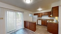 This updated two-story home in Memphis, Tennessee offers a well-designed layout across two floors. The main level features a bright, open living area with light wood-style flooring and a carpeted staircase with black metal railing leading to the upper level. Natural light flows in through windows near the front entry, creating a welcoming atmosphere. The kitchen is a functional highlight, equipped with warm-toned wood cabinetry, granite-style countertops, a peninsula with additional storage, and white appliances including a refrigerator, dishwasher, and electric range. A sliding glass door off the kitchen opens to a view of lush greenery, adding a pleasant outdoor connection. A convenient half bath on the main level features a wood-cabinet vanity with stone-style countertop and hardwood-style flooring. Upstairs, two carpeted bedrooms provide comfortable retreats, each with windows that allow natural light. The full bathroom on the upper level includes tile wall surround, a shower/tub combination, and a marble-style vanity countertop. Throughout the home, textured ceilings and neutral wall tones create a clean, move-in-ready environment suitable for comfortable everyday living.