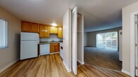Located at 672 Tamarack Dr in Union City, California, this single-floor residence offers a well-organized layout with a practical and comfortable design throughout. The kitchen is efficiently arranged in an L-shaped configuration, showcasing warm honey-toned wood cabinetry, granite countertops, and hardwood-style flooring. White appliances including a refrigerator, dishwasher, and electric range complete the space, while ample upper and lower cabinetry provides generous storage. A louvered bi-fold door separates the kitchen from adjacent areas, contributing to the open yet defined flow of the floor plan. The living area features plush carpeting, neutral-toned walls, and a textured ceiling, creating a cozy and inviting atmosphere. A ceiling fan with integrated lighting adds functionality, and vertical blinds frame a door that opens to an outdoor area, allowing natural light to filter in. The bathroom is appointed with a granite-topped vanity with wood cabinetry, a large mirror, and a frosted window that brings in soft natural light while maintaining privacy. Throughout the residence, a consistent material palette of warm wood tones, granite surfaces, and neutral walls ties the spaces together cohesively. Built-in closet storage with louvered doors provides practical organization solutions, rounding out this well-appointed single-level home.