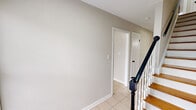 This two-story home in Indianapolis, Indiana offers a practical and well-organized layout across two floors. The main level features a kitchen equipped with warm wood cabinetry, black appliances including a gas range and refrigerator, a skylight for added brightness, and light tile flooring that extends into the hallway. A charming exposed brick accent wall adds character to the kitchen area. The staircase, featuring a dark wood banister and white balusters, connects both levels with a clean, classic look.

The upper floor is home to three bedrooms, all featuring rich hardwood flooring and neutral gray walls. The generously sized primary bedroom offers ample space and abundant natural light from multiple windows, along with a closet. The additional bedrooms are well-proportioned, each with hardwood floors and windows providing outdoor views. One living area includes light wood flooring and a large sliding glass door with vertical blinds, allowing for plenty of natural light. The two bathrooms are finished with tile flooring; one includes a full tub-shower combination with large beige wall tiles and a white vanity. Overall, the home presents a clean, neutral palette throughout, offering a functional and comfortable living environment.