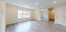This single-floor space is designed with a clean, modern aesthetic and a neutral palette of warm cream walls and light gray wood-look flooring that flows consistently throughout. The open layout is evident from the floor plan, with generously sized living areas that connect naturally to the rest of the unit, creating a spacious and airy feel.

The kitchen is a standout feature, outfitted with rich cherry wood cabinetry, granite countertops, a tile backsplash, and a full suite of stainless steel appliances including a gas range, built-in microwave, dishwasher, and refrigerator. A deep undermount sink completes the functional workspace.

The living and bedroom areas benefit from large windows that invite natural light and offer views of surrounding greenery. Recessed lighting throughout adds to the bright, welcoming ambiance.

The bathroom is finished with elegant marble-style wall tiling, a granite-topped vanity with cherry wood cabinetry, a framed mirror, and porcelain tile flooring. A spacious walk-in closet with built-in shelving and dual hanging rods provides excellent storage. The entry area features multiple doors, including a double-door closet, adding further practicality to the layout.