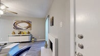 This two-story, two-bedroom, one-bathroom home offers a thoughtfully arranged layout spread across two floors. The main level hosts the living room, kitchen, and a dedicated laundry area, while the upper level is home to both bedrooms and the full bathroom.

The living room is a welcoming space featuring wood-look flooring, a white brick fireplace, a ceiling fan, and a sliding glass door that fills the room with natural light. A staircase leads to the upper floor, adding architectural character to the open layout.

The kitchen is outfitted with grey shaker-style cabinetry, a subway tile backsplash, light countertops, a stainless steel sink, and a dishwasher. Wood-look flooring continues throughout, creating a clean and cohesive aesthetic.

A dedicated laundry room with a washer/dryer hookup and built-in shelving adds practical convenience to the main floor.

Upstairs, the spacious primary bedroom features plush carpeting, a ceiling fan, and ample room for a full furniture arrangement. The second bedroom is similarly comfortable and well-proportioned with soft carpeting.

The bathroom is finished with a grey wood-tone vanity, white countertop, a large mirror, and wood-look tile flooring. A textured ceiling is present throughout the home, adding a classic residential touch.