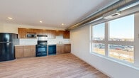 Located at 19699 Station St in Big Lake, MN, this 2-bedroom, 1-bathroom residence offers a well-designed single-floor layout with a clean, contemporary aesthetic. The open-concept kitchen and living area serves as the heart of the home, featuring warm medium-toned wood cabinetry, light countertops, and a full suite of black appliances including a refrigerator, range, microwave, and dishwasher. Recessed lighting and large windows fill the space with natural light, while exposed metal ductwork adds an industrial character to the design. Durable wood-look luxury vinyl plank flooring runs throughout the main living areas, complementing the neutral wall palette. The living room benefits from oversized windows that frame views of the surrounding Big Lake neighborhood. Both bedrooms are carpeted for comfort, with the primary bedroom offering a walk-in closet equipped with wire shelving on both sides. The second bedroom features a built-in double closet with modern panel doors. The full bathroom includes a tub/shower combination, wood-toned storage cabinetry, and clean tile flooring. A dedicated walk-in closet with hardwood-style flooring and dual wire shelving systems provides additional storage. The overall ambiance is bright, functional, and move-in ready.