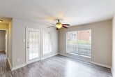This 1-bedroom, 1-bathroom unit offers a practical and efficient layout across a single floor. The interior is finished with light gray hardwood-style flooring throughout, lending a clean and cohesive look to the entire space.

The living area is bright and open, featuring neutral beige walls and a classic ceiling fan with a light fixture, adding both function and a touch of warmth. A glass-paneled exterior door allows natural light to filter in and provides access to the outside. A generously sized closet offers practical storage within easy reach.

The galley-style kitchen is well-equipped with white cabinetry lining both sides, offering ample storage and counter space. White appliances, including a coil-top electric range and a full-size refrigerator, are neatly integrated alongside a stainless steel sink. The layout is efficient, making excellent use of the available space.

The bedroom is a comfortable, well-proportioned room featuring the same hardwood-style flooring, neutral walls, and a ceiling fan overhead, creating a calm and restful atmosphere.

The bathroom is clean and straightforward, featuring a full-size soaking tub and shower combination with white tile surround, chrome fixtures, and a classic toilet. The warm-toned flooring adds a subtle contrast to the bright white fixtures, completing the space with a tidy, functional finish.