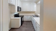Located at 1311 Deerpark Dr in Fullerton, California, this single-floor residence offers a well-organized layout with a blend of practical finishes and comfortable living spaces throughout. The open living area is highlighted by rich wood-style flooring, a ceiling fan with light fixture, and a textured ceiling, with a sliding glass door that invites natural light and provides outdoor access. Adjacent to the living area, the kitchen features white cabinetry extending to the ceiling for ample storage, light countertops, a double stainless steel sink, and black appliances including an electric range with overhead microwave. A pass-through or peninsula connects the kitchen to the main living space, enhancing the open feel. The bedrooms are finished with soft wall-to-wall carpeting and feature sliding closet doors, windows with outdoor views, and textured ceilings. The bathroom is well-appointed with a dual-sink vanity topped with a wide mirror and bright overhead lighting, white cabinetry below for storage, and a separate water closet housing a tub and shower combination enclosed by frosted glass sliding doors. Wood-style flooring continues through the bathroom and hallway, providing a cohesive look. The overall aesthetic is clean and neutral, making this a move-in ready space in a residential Fullerton neighborhood.