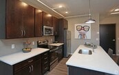 This 480 square foot apartment, located at 824 Broadway St in Cincinnati, OH, offers a well-designed living space on a single floor. The kitchen is a standout feature, boasting modern stainless steel appliances, including a refrigerator and built-in microwave. Rich, dark wood cabinetry contrasts beautifully with light countertops, creating a sleek and contemporary aesthetic. The bathroom impresses with its large glass-enclosed shower, featuring marble-like tiling and built-in shelving for convenience. Throughout the apartment, warm wood-look flooring adds a touch of elegance and continuity. Large windows in both the kitchen and living area flood the space with natural light and offer views of the surrounding cityscape. The living area, while compact, feels spacious due to high ceilings and an open-concept design. A closet provides essential storage space. The overall ambiance is one of urban sophistication, perfectly suited for those seeking a modern, low-maintenance lifestyle in the heart of Cincinnati.
