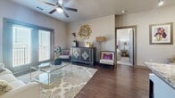 Located at 13920 Mandolin Drive in Houston, TX, this single-story residence offers a well-designed layout with contemporary finishes throughout. The kitchen is a standout feature, showcasing rich dark cabinetry, granite countertops, stainless steel appliances including a range, microwave, refrigerator, and dishwasher, along with a central island with a sink and pendant lighting overhead. Wood-style flooring runs through the main living and kitchen areas, adding warmth and continuity. A dedicated laundry area with a full-size washer is conveniently tucked just off the kitchen. The living area is generously proportioned, featuring a ceiling fan and windows dressed with horizontal blinds that invite natural light. Multiple bedrooms are present, each carpeted and filled with natural light from large windows. The primary bedroom is a comfortable retreat, while additional bedrooms offer equal comfort and versatility. Each bedroom connects to a well-appointed bathroom featuring granite-topped dark vanities, framed mirrors, and wood-style flooring. A spacious walk-in closet with wire shelving and rod storage completes the primary suite, providing ample organization. The overall aesthetic is cohesive and modern, with neutral tones and quality finishes throughout.