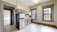 Located at 35 Union St in New London, Connecticut, this single-floor unit combines classic architectural character with modern updates. The kitchen serves as a functional centerpiece, outfitted with gray raised-panel cabinetry, a mosaic tile backsplash in neutral tones, stone-look countertops, and stainless steel appliances including a refrigerator and range. Two multi-pane windows frame views of the surrounding urban streetscape, filling the space with natural light. Light wood-style luxury vinyl flooring runs throughout the unit, creating a clean, cohesive aesthetic. The bedroom features generous proportions, a closet with built-in shelving, and classic gray-trimmed panel doors that echo the home's traditional character. Additional windows in the bedroom continue to bring in natural light and views of the neighborhood. The bathroom is well-appointed with a full soaking tub and shower combination, a classic toilet, light flooring, and a window that provides ventilation and brightness. Baseboard heating units are present throughout, ensuring year-round comfort. The overall ambiance is one of updated, move-in-ready comfort with nods to the building's historic New England roots, making it an informative and practical choice in downtown New London.