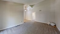 Located in San Marcos, CA, this single-floor, 3-bedroom, 2-bathroom unit offers a practical and well-organized layout. The living room is a standout space, featuring soaring vaulted ceilings and a ceiling fan that enhance the sense of openness. Soft carpeting flows throughout the living and bedroom areas, creating a comfortable atmosphere. The three bedrooms are bright and inviting, each benefiting from large windows dressed with blinds that allow natural light while offering privacy, with views of surrounding greenery. The primary bedroom includes a sliding-door closet for convenient storage. The kitchen is outfitted with white cabinetry, light-toned countertops, a double-basin stainless steel sink, and a window above the sink that brings in natural light. A dishwasher and refrigerator are also present. The two bathrooms are clean and functional; one features a tub-shower combination with a curtain, while the other includes a vanity with a stone-finish countertop and wood-look flooring. A hallway connects the main living areas to the bedrooms and bathrooms, providing a logical flow throughout the unit. The textured ceilings and neutral wall tones throughout contribute to a cohesive, understated aesthetic.