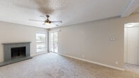 This single-floor unit offers a well-organized layout that balances comfort and functionality throughout its living spaces. The main living area is a generous, carpeted room highlighted by a textured ceiling, a ceiling fan with light fixture, and a tile-surround fireplace that serves as a focal point. A sliding glass door and an adjacent window allow natural light to fill the room and provide access to a balcony with outdoor views.

The kitchen is designed in a galley style, featuring gray cabinetry, granite-style countertops, wood-look flooring, a subway tile backsplash, and black appliances including an electric range and refrigerator. A peninsula counter with a breakfast bar connects the kitchen to the adjacent living and dining area, creating an open and practical flow. The entry door opens directly into this combined living and kitchen zone.

The bedroom is a comfortable, carpeted room with its own ceiling fan, a window with balcony views, and a clean, neutral palette. The bathroom is well-appointed with wood-look tile flooring, a gray vanity with a granite-style countertop, and a full tub-shower combination featuring large-format tile surround and brushed nickel fixtures. Throughout the unit, neutral tones and consistent finishes create a cohesive and move-in-ready atmosphere.