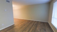This single-floor space presents a straightforward and functional layout designed to accommodate a variety of uses. The interior is characterized by rich, warm-toned hardwood flooring that runs throughout, adding a sense of natural warmth and durability underfoot. The planks display a classic wood grain pattern with subtle variation in tone, contributing to a grounded, inviting aesthetic.

The walls are finished in a soft, neutral palette — a muted sage or warm beige — that complements the flooring and creates a calm, understated atmosphere. Clean white baseboards provide a crisp contrast along the floor line, lending a tidy, well-maintained appearance to the space.

The room benefits from a smooth, white ceiling that reflects light evenly across the interior. The overall ambiance is open and uncluttered, making it highly adaptable for a range of furniture arrangements or functional purposes. The absence of ornamentation keeps the focus on the quality of the core finishes, particularly the hardwood floors and the consistently painted walls.

Electrical outlets are positioned at standard heights along the walls, offering practical utility throughout. The space presents a blank canvas with solid foundational finishes, making it an excellent starting point for customization or move-in readiness.