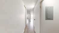 Located at 6880 Boulevard Gouin Est in Montréal-Nord, this well-organized one-bedroom, one-bathroom unit offers a clean and functional layout across a single floor. Light wood-style flooring runs throughout the main living areas, complementing the bright white walls and creating a cohesive, airy atmosphere.

The combined kitchen and living area forms the heart of the unit. The living space benefits from a large sliding glass door that opens to a private balcony, allowing natural light to pour in and providing open views of the surrounding neighbourhood. The kitchen is efficiently designed with white cabinetry featuring black hardware, granite-style countertops, a tile backsplash, and white appliances including a stove and refrigerator. Light tile flooring ties the kitchen together.

A hallway connects the living areas to the private bedroom, which is generously sized and features a window for natural light, baseboard heating, and direct access to a dedicated walk-in closet equipped with built-in shelving for ample storage.

The bathroom is finished in a clean, all-white palette with a tiled tub-shower combination, a granite-topped vanity with an integrated sink, and a mirrored medicine cabinet. Textured ceilings are present throughout, adding a subtle architectural detail to the overall clean and practical design of the unit.