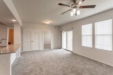 Located at 5400 Overland Dr in Lawrence, Kansas, this single-floor residence offers a well-designed open-concept layout that seamlessly connects the living and kitchen areas. The carpeted living room is bright and spacious, equipped with a ceiling fan and sliding glass door that opens to a private balcony, allowing for natural light and outdoor access. A large bank of windows further enhances the airy feel of the space.

The kitchen is a standout feature, showcasing rich dark wood cabinetry, granite countertops, a classic white subway tile backsplash, and a full suite of stainless steel appliances including a refrigerator, electric range, and over-the-range microwave. A peninsula with a sink provides additional counter space and casual seating potential, making it ideal for both cooking and entertaining.

The bedrooms are carpeted and generously sized, each fitted with ceiling fans. The primary bedroom includes a walk-in closet, while a secondary bedroom offers ample space and natural light through blinded windows. The bathroom is well-appointed with dark wood vanity cabinetry, granite countertops, a dual-sink layout, tile flooring, and a full soaking tub with built-in shelving. The entry stairwell leads up to the unit with a warmly lit foyer entrance, adding a welcoming touch to the overall design.