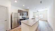 Located at 2425 Premier Dr in Plano, TX, this one-bedroom, one-bathroom unit offers a thoughtfully designed layout across a single floor. Wood-look flooring runs consistently throughout the space, lending warmth and visual continuity from room to room.

The kitchen is a standout feature, equipped with stainless steel appliances including a refrigerator, electric range, and microwave. Dark espresso cabinetry is paired with granite-style countertops, providing ample storage and prep space. Recessed lighting illuminates the kitchen, which connects directly to the main living area via an open passageway.

The bedroom is a comfortable size, featuring two windows that allow natural light to filter in and offer views of surrounding greenery. A ceiling fan adds practical comfort, and the room connects to a dedicated closet and hallway access.

The bathroom continues the cohesive design aesthetic with matching dark cabinetry, a granite-topped vanity, wood-look flooring, and a shower-tub combination set against clean white walls. Two hallways provide efficient circulation throughout the unit.

Overall, the space presents a clean, modern aesthetic with consistent finishes, practical storage, and a functional flow well-suited for single occupancy living in Plano.
