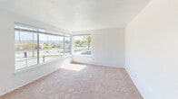 Located at 105 Anoka Ave in Bremerton, WA, this single-floor unit offers three bedrooms, one bathroom, a living room, and a hallway, all finished with consistent wall-to-wall carpeting and clean white walls throughout. The living room is the largest area of the unit, featuring a textured ceiling, a wall-mounted heater vent, and a window that brings in natural light. A hallway connects the living area to the rest of the unit. The primary bedroom is the most spacious of the three, offering a sliding-door closet with a built-in shelf and hanging rod. The second bedroom features a wide window with outdoor views of the surrounding neighborhood, a wall-mounted heater, and a ceiling light fixture. The third bedroom is smaller and benefits from natural light streaming through its window, accompanied by a ceiling light. All bedrooms are carpeted and feature clean, neutral white walls. The full bathroom is equipped with a tub and shower combination fitted with a curved curtain rod and brushed nickel fixtures. The unit's compact, efficient layout and bright, neutral interior make it a functional and straightforward living space in a convenient Bremerton location.