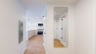 Located at 95 Anderson St in Hackensack, NJ, this thoughtfully designed 2-bedroom, 3-bathroom residence offers a clean, modern aesthetic across a single floor. Light oak hardwood flooring and crisp white walls run throughout, creating a bright and cohesive atmosphere.

The open-concept living room is generously proportioned, featuring large windows on multiple walls that flood the space with natural light and offer views of the surrounding neighborhood. Adjacent to it, the dining area benefits from the same expansive windows, making it an airy, inviting space.

The kitchen is outfitted with high-gloss white cabinetry, stainless steel appliances including a gas range and French door refrigerator, and a white quartz peninsula with bar seating — ideal for both everyday living and entertaining.

The primary bedroom is a well-sized, serene retreat with built-in closets featuring sleek black hardware. Both bedrooms maintain the same light, neutral palette. The three bathrooms are finished with large-format porcelain tiles, floating wood vanities, illuminated mirrors, and matte black fixtures, offering a refined, spa-like feel.

A full-length mirror and clean entryway hallway complete the well-organized layout of this modern Hackensack residence.
