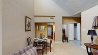 Located at 15035 Westpark Dr in Houston, Texas, this single-story residence offers a well-designed layout with a warm, neutral color palette throughout. The living room is a standout space, boasting dramatically vaulted ceilings, a ceiling fan, a tiled fireplace, and large windows that invite natural light. Plush carpeting and an open flow into the dining area make this an inviting gathering space. The dining area connects seamlessly to the kitchen, which features a galley-style layout with rich wood cabinetry, tile backsplash, laminate countertops, hardwood-style flooring, and a full suite of appliances. Two bedrooms provide comfortable retreats, each with vaulted ceilings, carpeted floors, and windows with blinds. The primary bedroom includes a private door leading to an outdoor space. Two bathrooms are present, each equipped with a tub-shower combination and wood cabinetry. Additional highlights include a tiled entryway, closet storage, and a cohesive design that balances functionality with a comfortable residential ambiance throughout the single-floor plan.