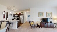 Located at 457 Dutch Meadows Ln in Schenectady, NY, this single-floor residence offers a well-designed, open-concept layout that seamlessly connects the kitchen, dining, and living areas. The kitchen is appointed with dark espresso cabinetry, stainless steel appliances including a refrigerator, microwave, and range, and a granite-topped island with pendant lighting overhead. Hardwood-style flooring anchors the kitchen and dining area, while plush carpeting extends through the living room and hallways, creating a warm and comfortable atmosphere. The living room is generously proportioned, featuring neutral walls that allow for flexible styling and access to natural light through large windows. A dedicated dining space sits adjacent to the main living area, providing a functional and inviting setting for meals. The two bedrooms are bright and well-sized, each benefiting from large windows that bring in abundant natural light and outdoor views. The primary bedroom is notably spacious with direct exterior access. Two bathrooms serve the residence, each finished with tile flooring, a tub-shower combination, and clean white vanities with ample storage. Built-in shelving in the bathroom adds practical organizational space. The overall design is clean, modern, and move-in ready.