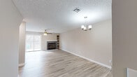 This two-floor residence offers a well-organized layout designed for comfortable everyday living. The main level features an open living area finished with light wood-style flooring that extends throughout, anchored by a striking stone-surround fireplace with built-in shelving on one side and a sliding glass door that fills the room with natural light. A ceiling fan adds a practical touch to the spacious living room. Adjacent to the living area, the dining space is illuminated by an elegant chandelier and connects seamlessly to the kitchen via a pass-through opening. The kitchen is equipped with white cabinetry, light countertops, a stainless steel sink, a dishwasher, and an electric range, all set over matching light wood-style flooring. A staircase with carpeted treads leads to the upper level, where the bedrooms are located. Each bedroom features plush carpeting, ceiling fans, natural light from windows, and mirrored sliding closet doors with gold-tone frames. The primary bedroom benefits from a private sliding glass door that opens to a balcony with wooded views. Throughout the home, neutral warm-gray walls and textured ceilings provide a clean, cohesive backdrop that is move-in ready and easy to personalize.