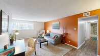 This single-floor residence offers a thoughtfully arranged layout that balances comfort and functionality across its living spaces. The living room immediately draws attention with a striking burnt-orange accent wall, neutral carpet, and wood-look flooring at the entry transition. A window provides natural light, and a textured ceiling adds architectural character throughout the unit.

The galley-style kitchen is efficiently designed with rich, dark espresso cabinetry lining both sides, granite-patterned countertops, black appliances including a refrigerator and electric range, and a double stainless steel sink. The kitchen opens directly toward a dedicated dining area, which features wood-look flooring, a ceiling fan with light fixture, and a window that brings in additional natural light—making it a bright and inviting space for meals.

The bedroom is carpeted and comfortably sized, featuring a window and a closet with louvered bifold doors offering practical storage. The full bathroom includes a tub-shower combination, a dark vanity cabinet, and wood-look flooring, maintaining the cohesive design aesthetic found throughout the unit.