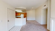 This single-story residence offers a thoughtfully arranged floor plan with a neutral, light-filled interior throughout. The living area is a standout space, featuring a built-in fireplace set against a tall accent wall and a sliding glass door that opens to an outdoor area, inviting natural light and views of surrounding greenery. Soft carpet flooring runs through the living and bedroom areas, contributing to a warm, comfortable ambiance.

The kitchen is well-appointed with warm-toned wood cabinetry extending to the ceiling for ample storage, white appliances including a range and microwave, a dual-tone countertop, and a skylight overhead that brightens the workspace. A half-wall peninsula separates the kitchen from the adjacent living space, creating an open, connected feel. Tile flooring and hardwood-style vinyl complete the kitchen's functional design.

The bedrooms are generously sized, with large windows fitted with vertical blinds that frame outdoor views, and at least one bedroom includes a mirrored sliding-door closet. The bathrooms feature white cabinetry, speckled countertops, tiled tub-shower combinations, and hardwood-style flooring. The property also includes a sizable green lawn area visible in the exterior overview.